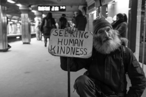 Photographer met a man on the subway. The man has a sign that reads "seeking human kindness".