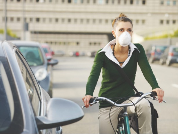 Woman with dust mask commuting on a bicycle.