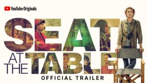 Seat at the Table title card with diverse images of people and nature set into the letters, and a man standing behind a fold-up chair.